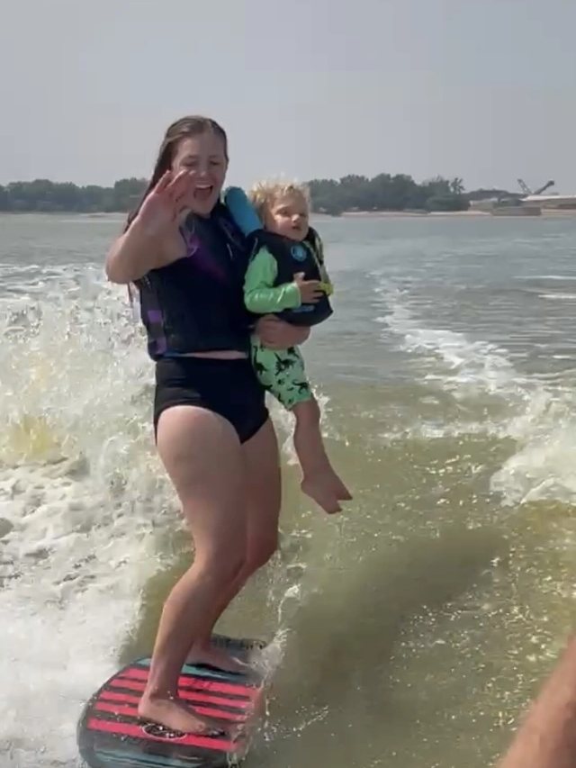 Dr. Lyle lake surfing with her toddler on her hip